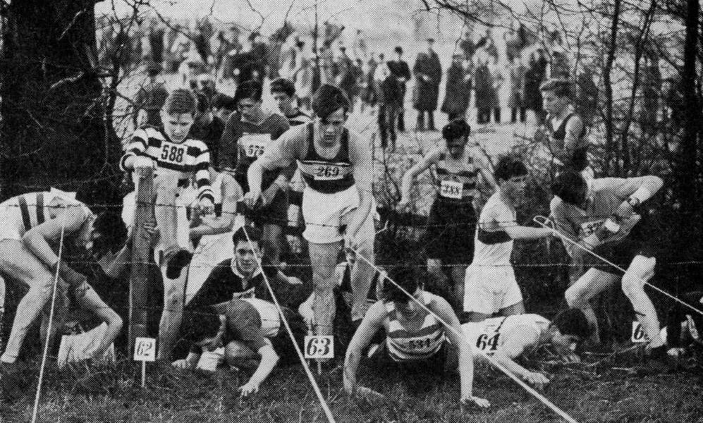 Youths try to get over or through a barbed wire fence near the start